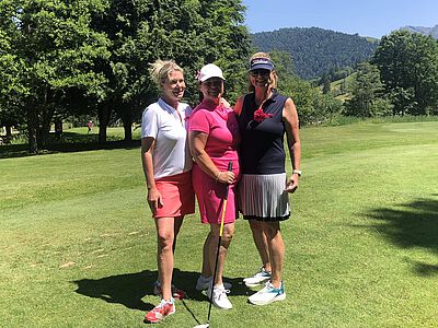 Drei Damen, teilweise in pink auf dem Golfplatz.