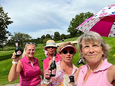 Vier Damen in pink auf einer grünen Wiese.